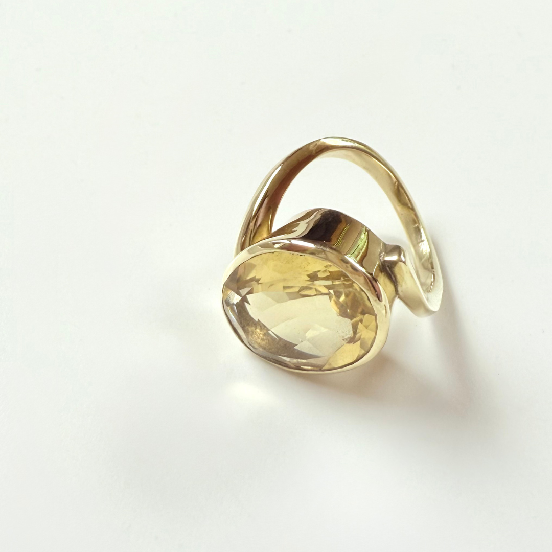 Gold ring with a yellow citrine gemstone on a white background