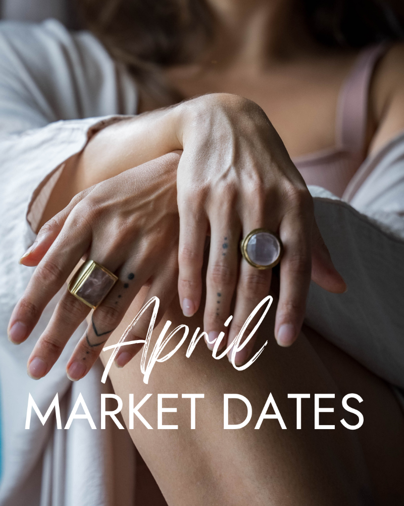 Close-up of hands with rings and text 'April Market Dates' on a blurred background