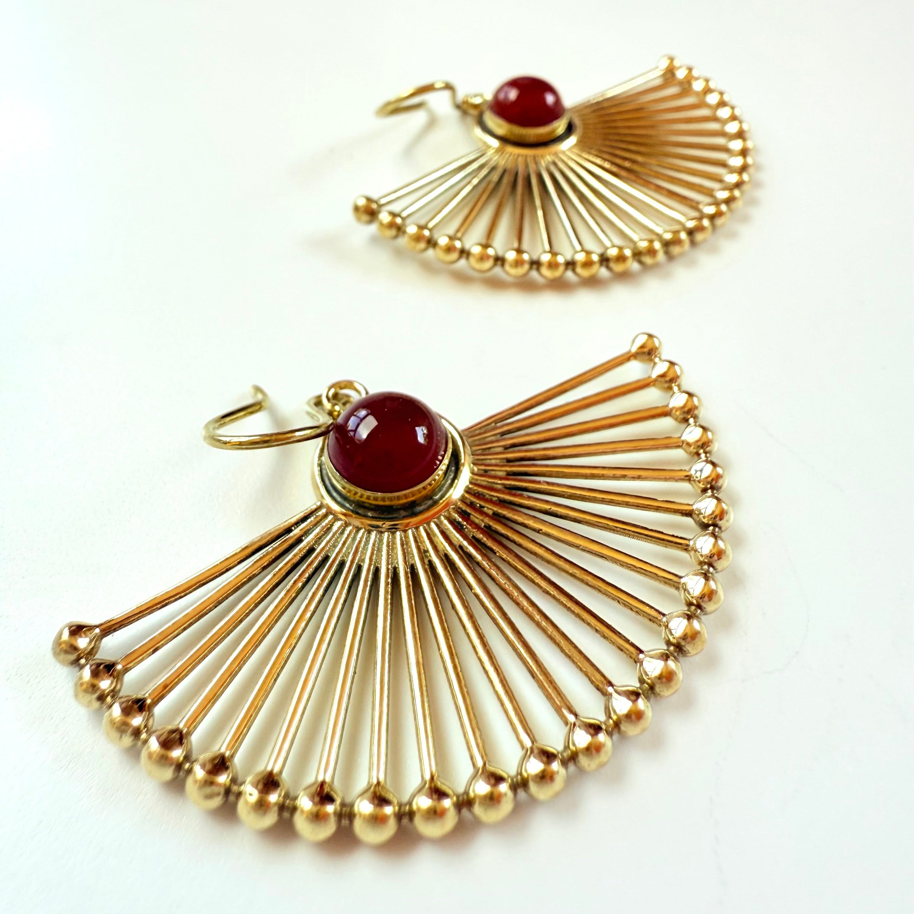 Gold earrings with red gemstones on a white background