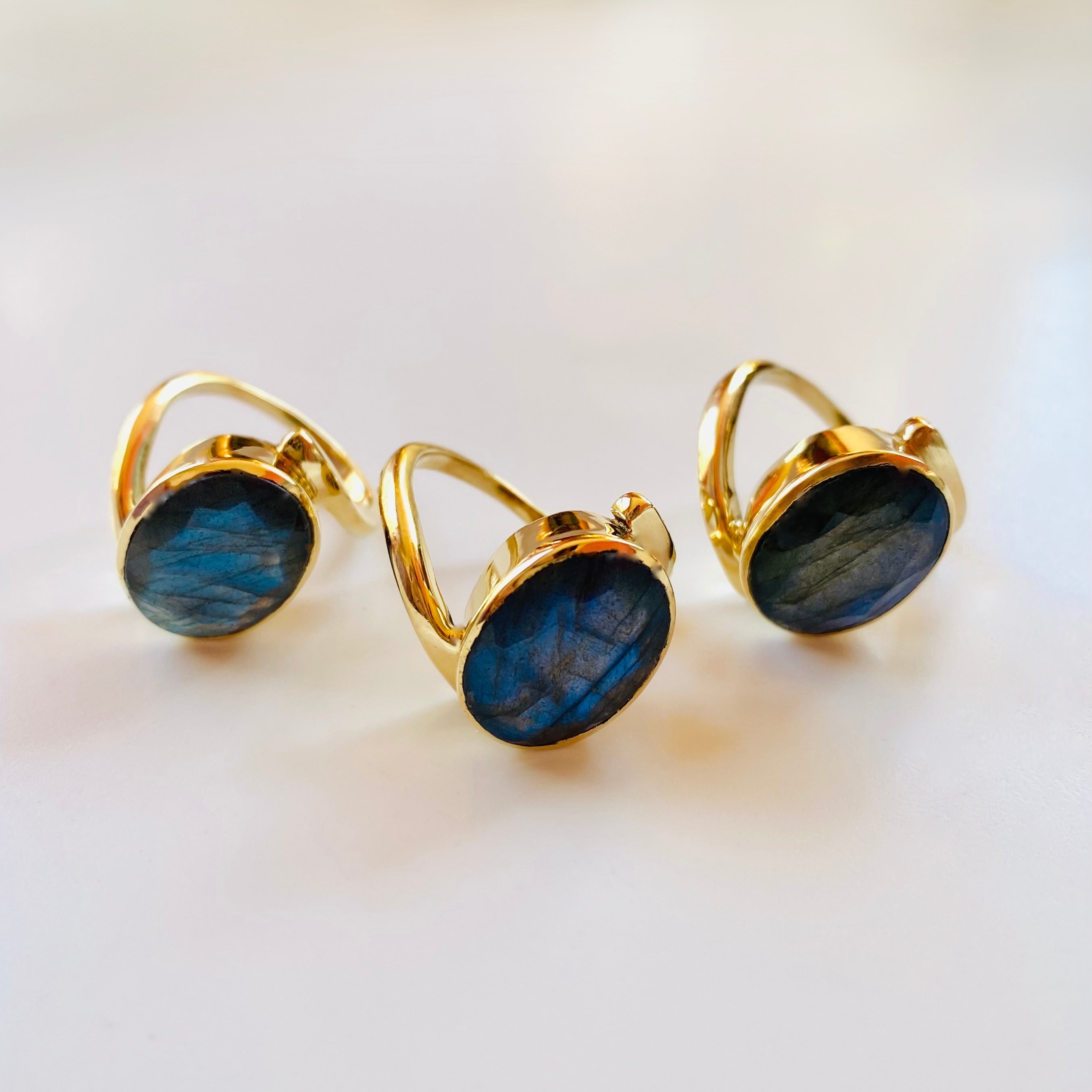 Gold-rimmed blue Labradorite gemstone rings on a white background