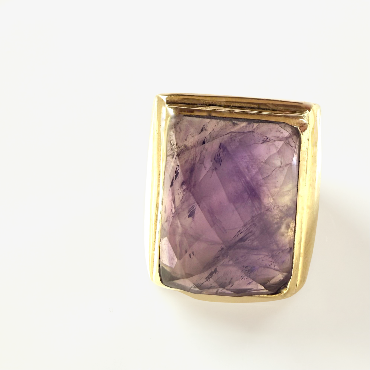 Gold ring with a large purple gemstone on a white background