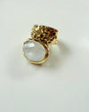 Gold ring with a large clear gemstone on a light gray background
