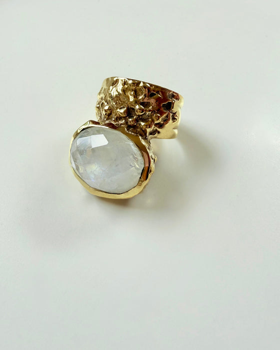 Gold ring with a large clear gemstone on a light gray background
