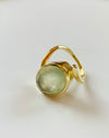 Gold ring with a green gemstone on a light background