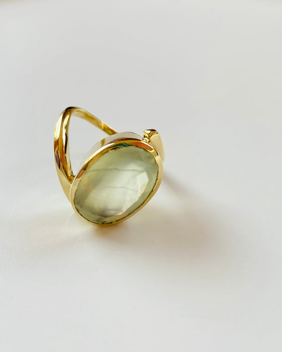 Gold ring with a green prehnite gemstone on a white background