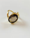 Gold ring with a smoky quartz stone on a light gray background