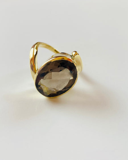 Gold ring with a smoky quartz stone on a light gray background
